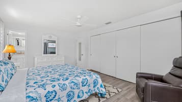 A bedroom with a bed, a desk, a chair, a wardrobe, and a ceiling fan.