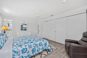Un dormitorio con una cama, un escritorio, una silla, un armario y un ventilador de techo.