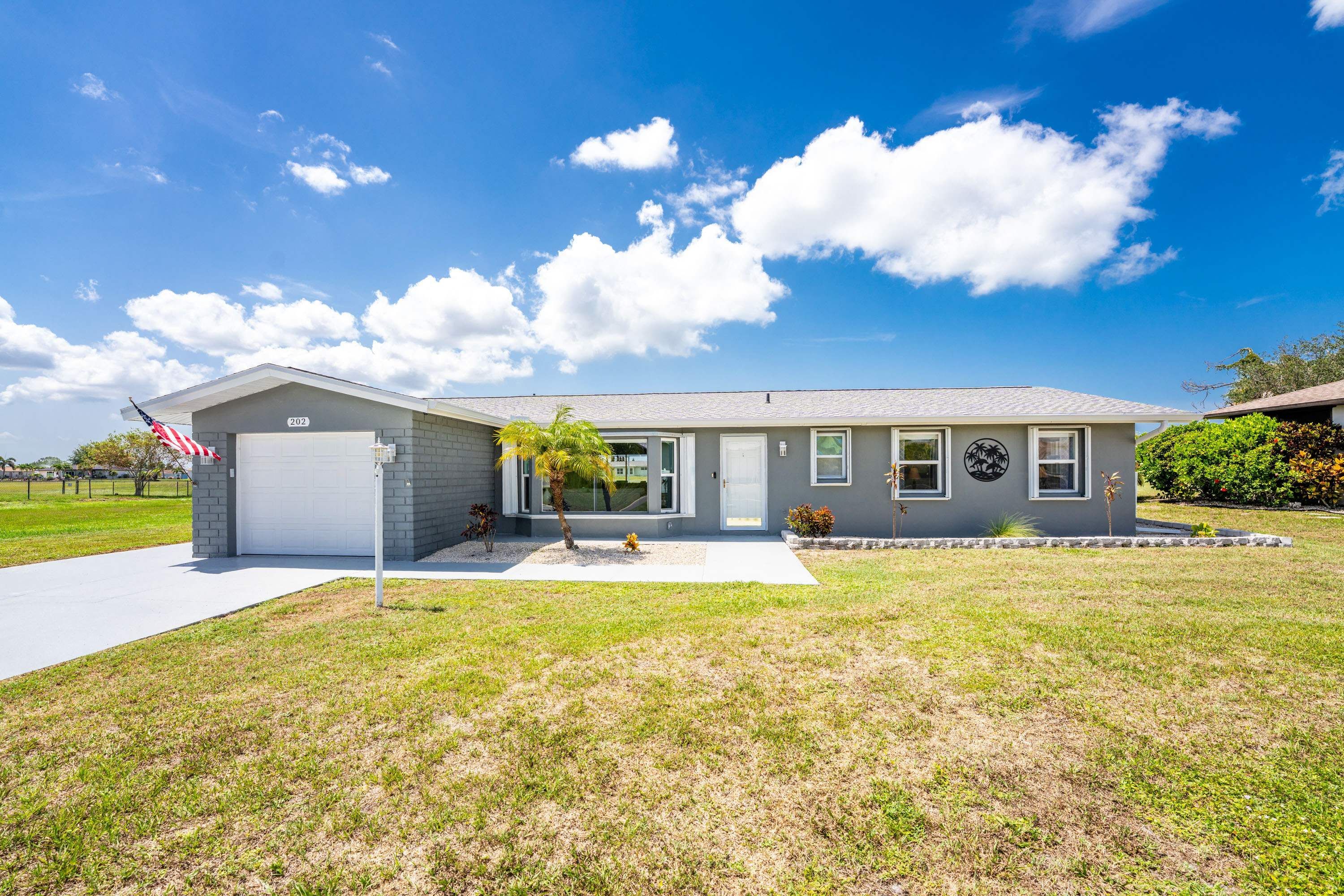 A single-story residential house with a garage, a small front yard, and a clear blue sky.