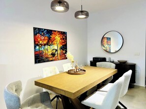A dining area with a wooden table, white chairs, a painting, a mirror, and pendant lights. - Boutique stay in Athens center (Athina)