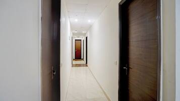 A corridor with a tiled floor, a wooden door on the right, and a red carpet leading to a room.