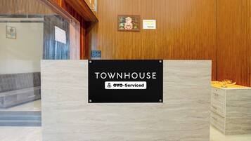 Un mostrador de recepción con un cartel que indica 'TOWNHOUSE' y 'OYO-Serviced'.