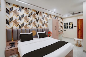 Habitación de hotel con cama, mesita de noche, armario y una pequeña mesa redonda con una silla.