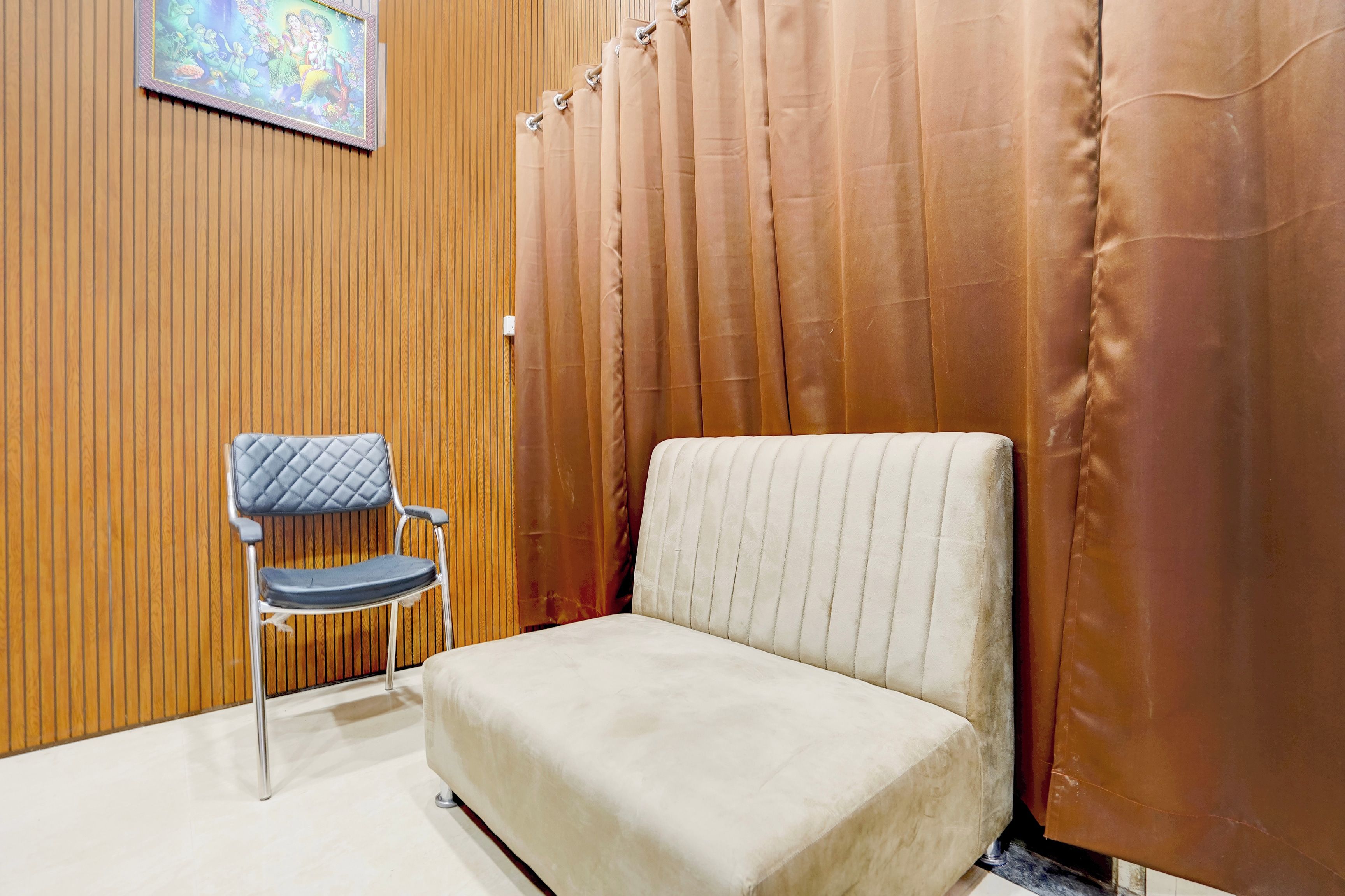 A room with a cushioned chair, a wooden panel wall, and a curtain.