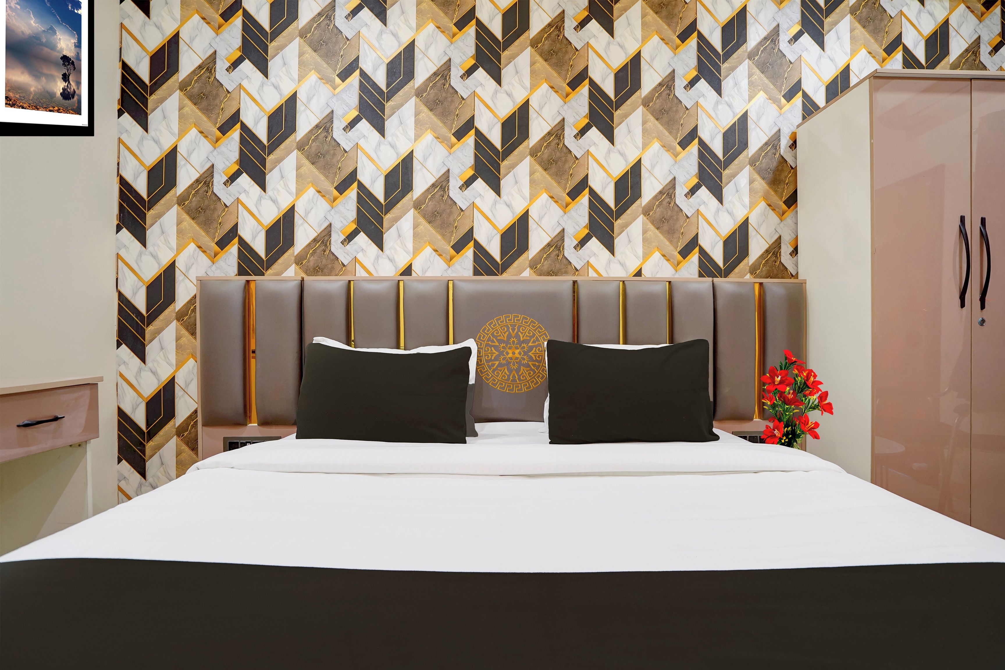 Una habitación de hotel con una cama, una mesita de noche, un armario y un diseño decorativo en la pared.