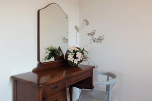 A wooden dresser with a mirror, two vases with flowers, and a chair. - A3 - Modern apartment with garden and balcony with sea view, 80m from beach (Vinišće)
