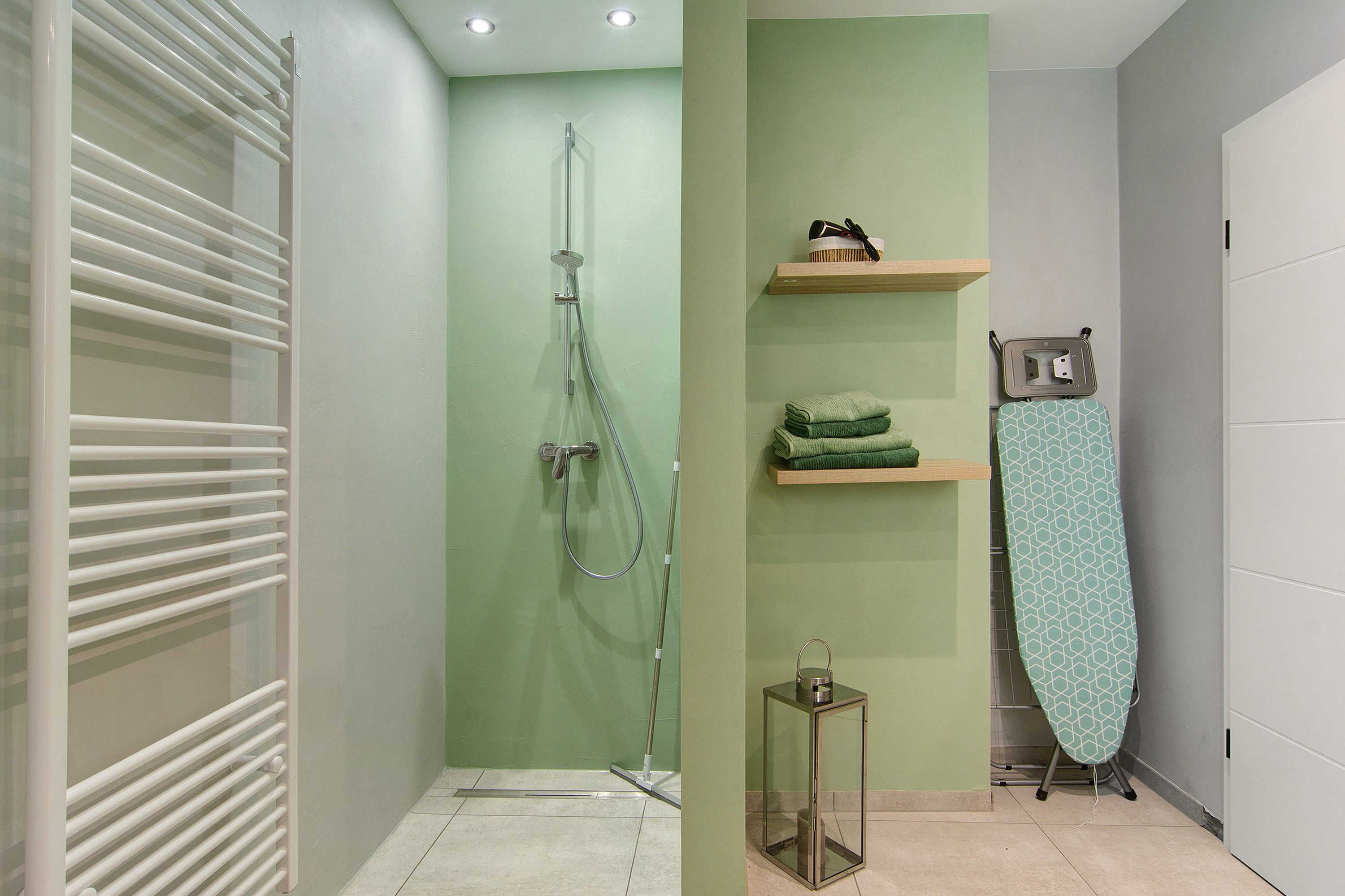 Ein Badezimmer mit Dusche, Handtuchhalter und einem kleinen Tisch.