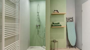 A bathroom with a shower, a towel rack, and a small table.