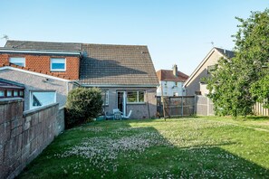 A residential property with a sloped roof, a brick exterior, and a grassy backyard with a patio area. - Warrack Street (No 37) | St Andrews (St Andrews)