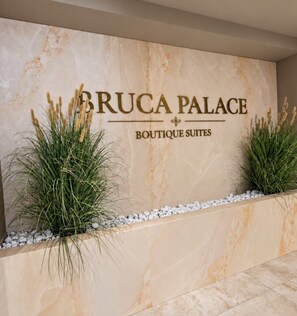 A marble wall with the text 'BRUCA PALACE BOUTIQUE SUITES' and two potted plants. - Bruca Palace Boutique Suite (Catania)