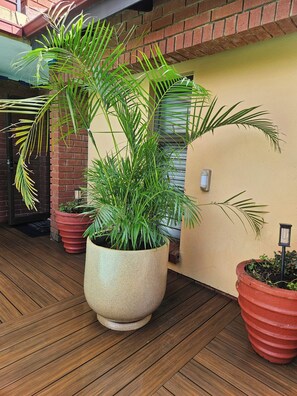 Una terraza de madera con plantas en macetas y una pared de ladrillo.