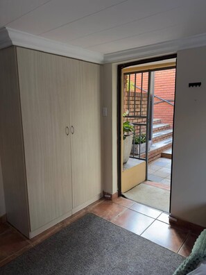 Una habitación con puerta corrediza que da a un balcón con pared de ladrillo y escalones.