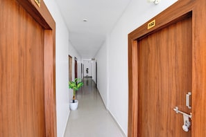 A hallway with wooden doors, a potted plant, and a sign indicating room number 102. - Hotel O Ayodhya Junction Road (Faizabad)