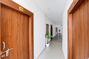 A corridor with wooden doors, a potted plant, and a sign indicating room number 103. - Hotel O Ayodhya Junction Road (Faizabad)