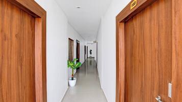 A hallway with wooden doors, a potted plant, and a sign indicating room numbers.
