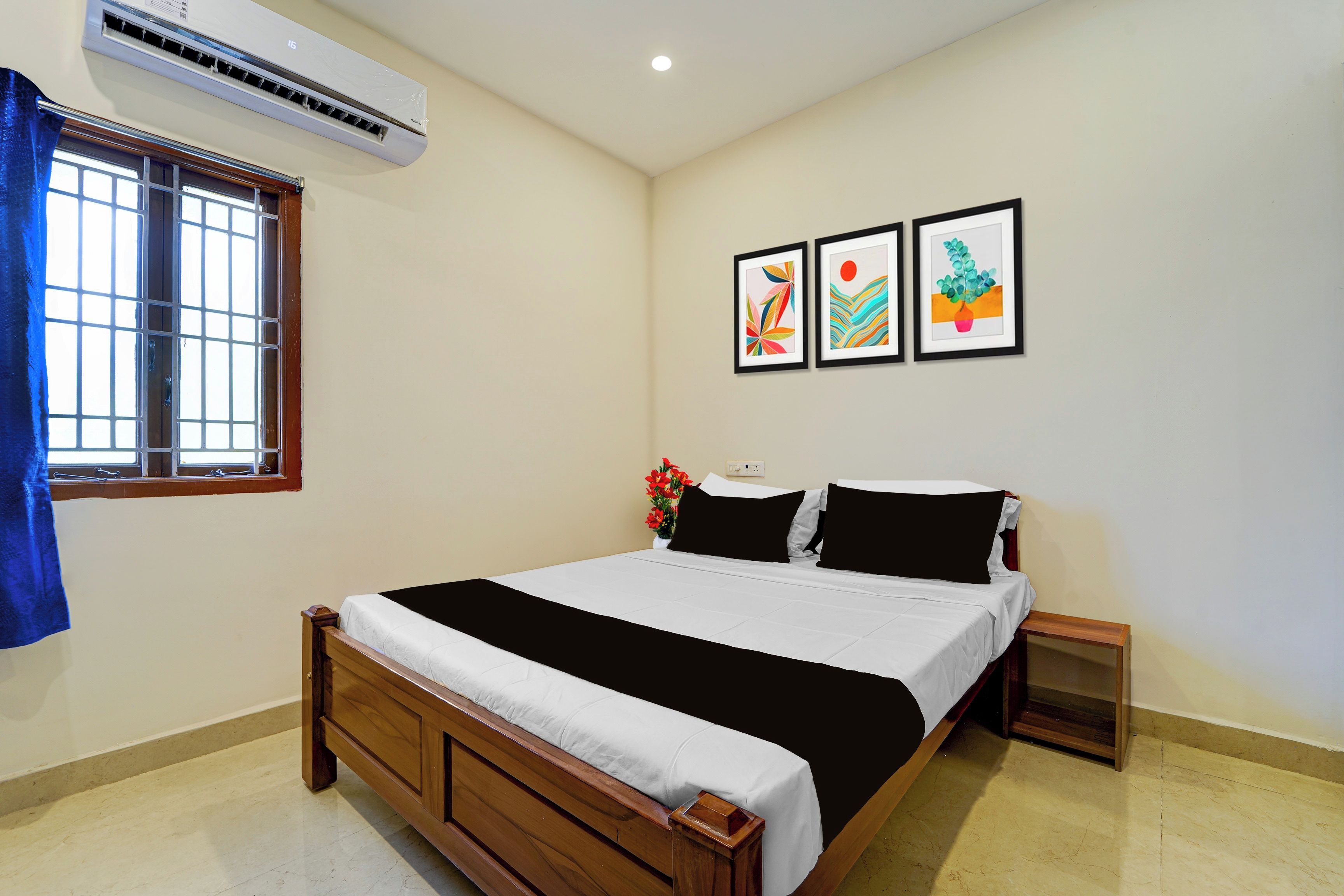 Un dormitorio con una cama, una ventana, aire acondicionado y tres cuadros enmarcados en la pared.