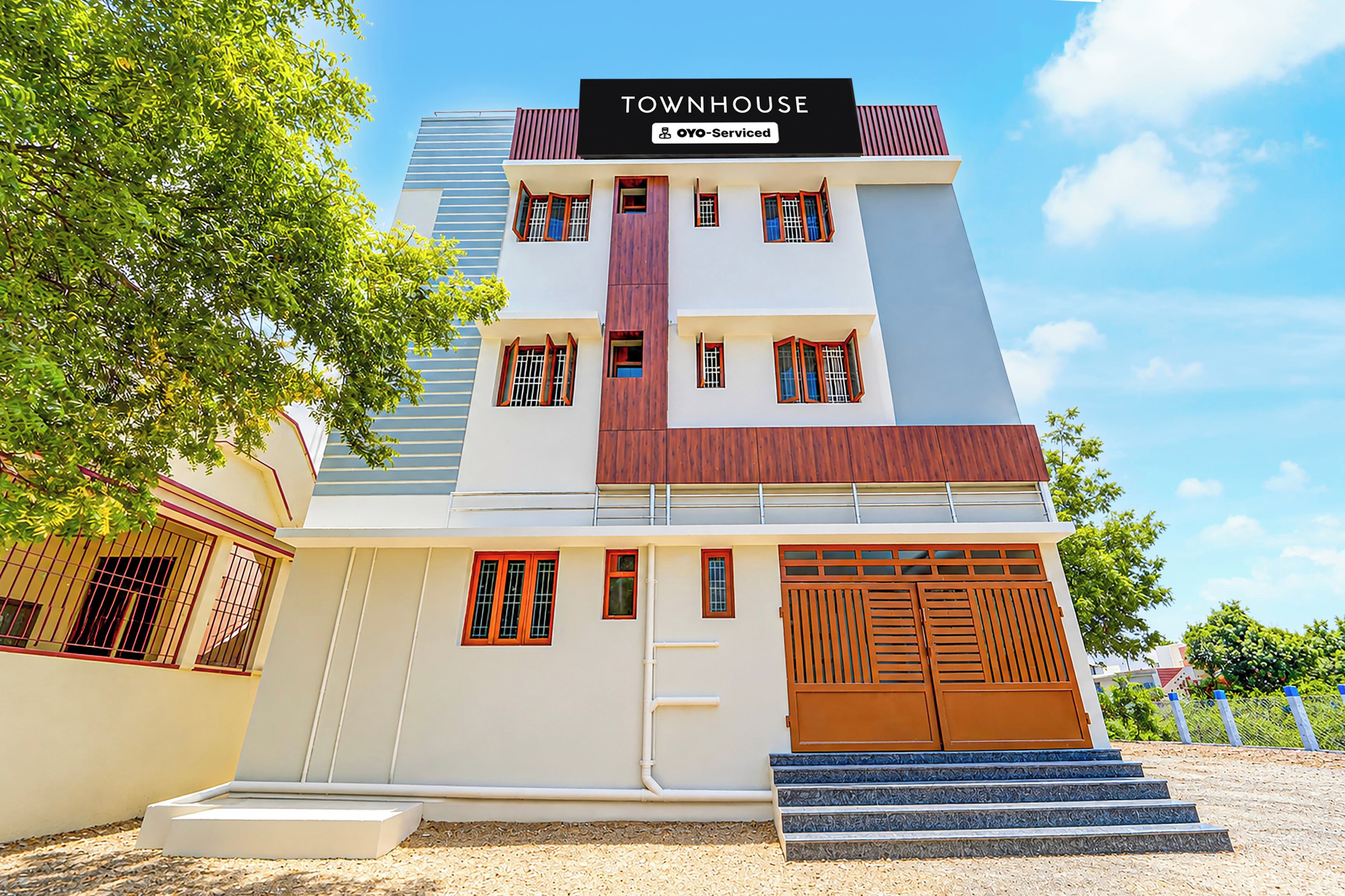 Un edificio de varios pisos con un letrero que dice 'TOWNHOUSE' y 'OYO-Serviced'.