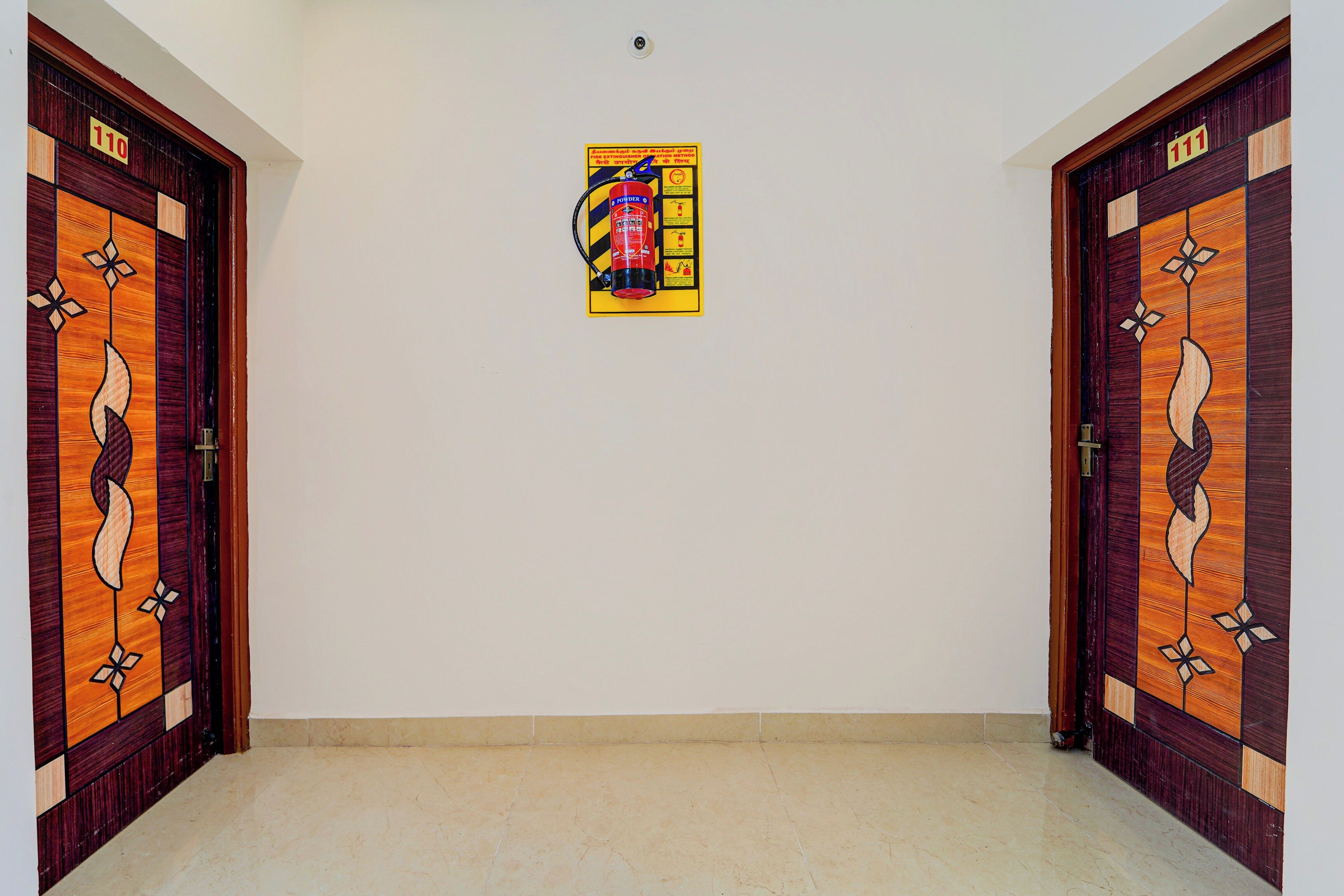 Un pasillo con dos puertas de madera, cada una con el número 110. Un cartel con instrucciones sobre el extintor está centrado en la pared.