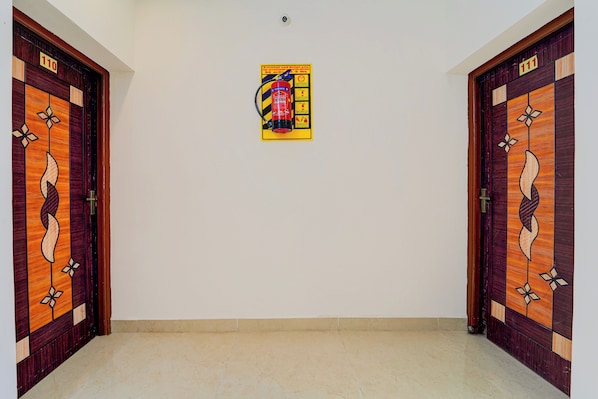 Un pasillo con dos puertas de madera, cada una con el número 110. Un cartel con instrucciones sobre el extintor está centrado en la pared.