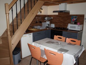 Eine Küche mit einer Holztreppe, einem Esstisch mit Stühlen und einer Mikrowelle auf der Arbeitsfläche.