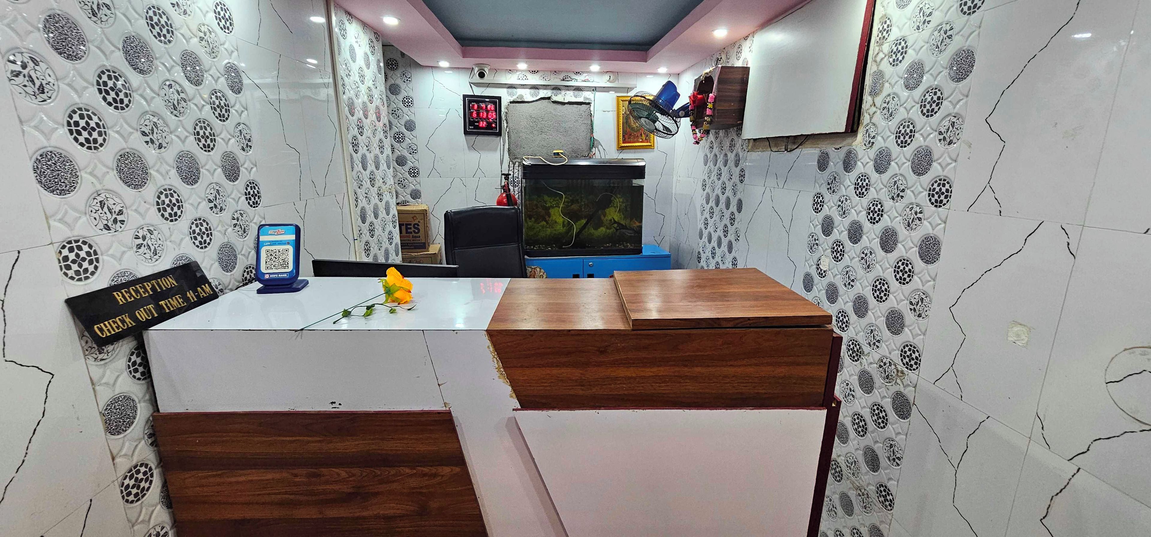 A reception area with a check-out time sign, a QR code stand, a fish tank, and a blue cabinet.