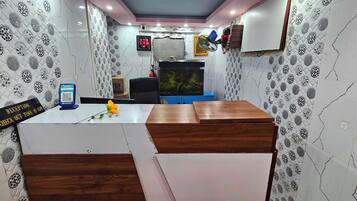 A reception area with a check-out time sign, a QR code stand, a fish tank, and a blue cabinet.