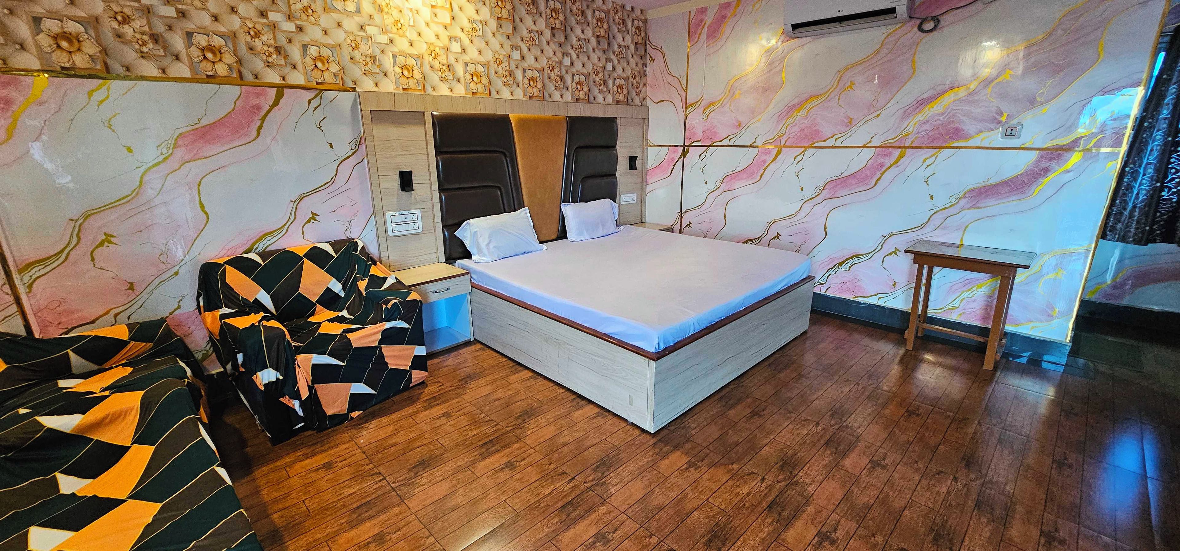 A bedroom with a bed, nightstand, dresser, and a patterned sofa.