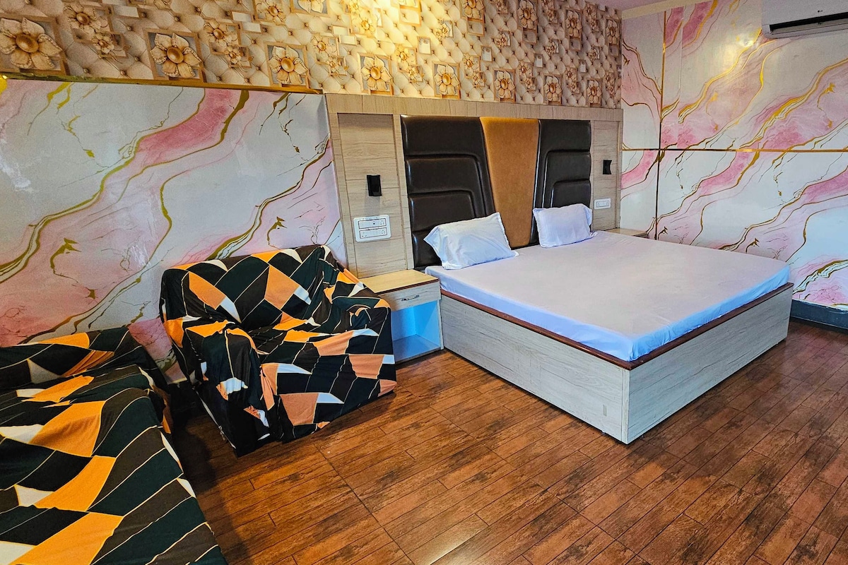 Un dormitorio con cama, mesita de noche, cómoda y sofá estampado.