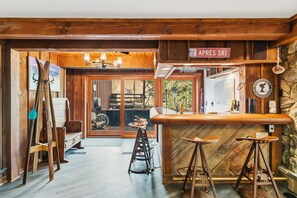 Un espace bar à thème ski, avec des meubles en bois, un porte-skis et une enseigne indiquant « APRÈS-SKI ».