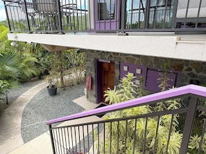 Ein mehrgeschossiges Gebäude mit einer Steinfassade, einer violetten Tür mit der Aufschrift 'Wascherei' und einem Balkon mit Geländer.