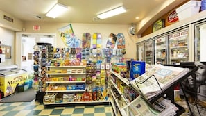 Ein Kiosk mit Regalen voller Snacks, einem Gefriertruhe und einer Zeitungsauslage.