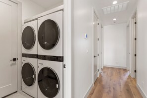 A laundry room with four washing machines and a hallway leading to other rooms. - Isle 64: Sleeps 10 + Rec Center Access! 4 Bedroom Townhouse (Washington)