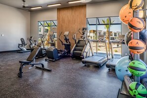 Een sportschool met diverse fitnessapparaten, een bank en trainingsballen.