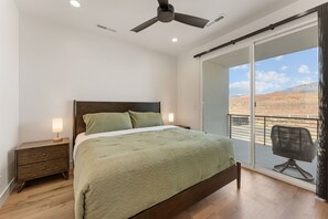 A bedroom with a bed, bedside table, lamp, and a view of a balcony with a chair. - Isle 64: Sleeps 10 + Rec Center Access! 4 Bedroom Townhouse (Washington)