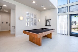 Een moderne biljarttafel binnen, met houten frame en zwart vilt, omgeven door witte muren en inbouwverlichting.