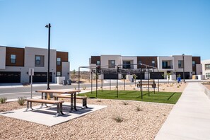 Uma área residencial moderna com um calçadão pavimentado, bancos e um parquinho.