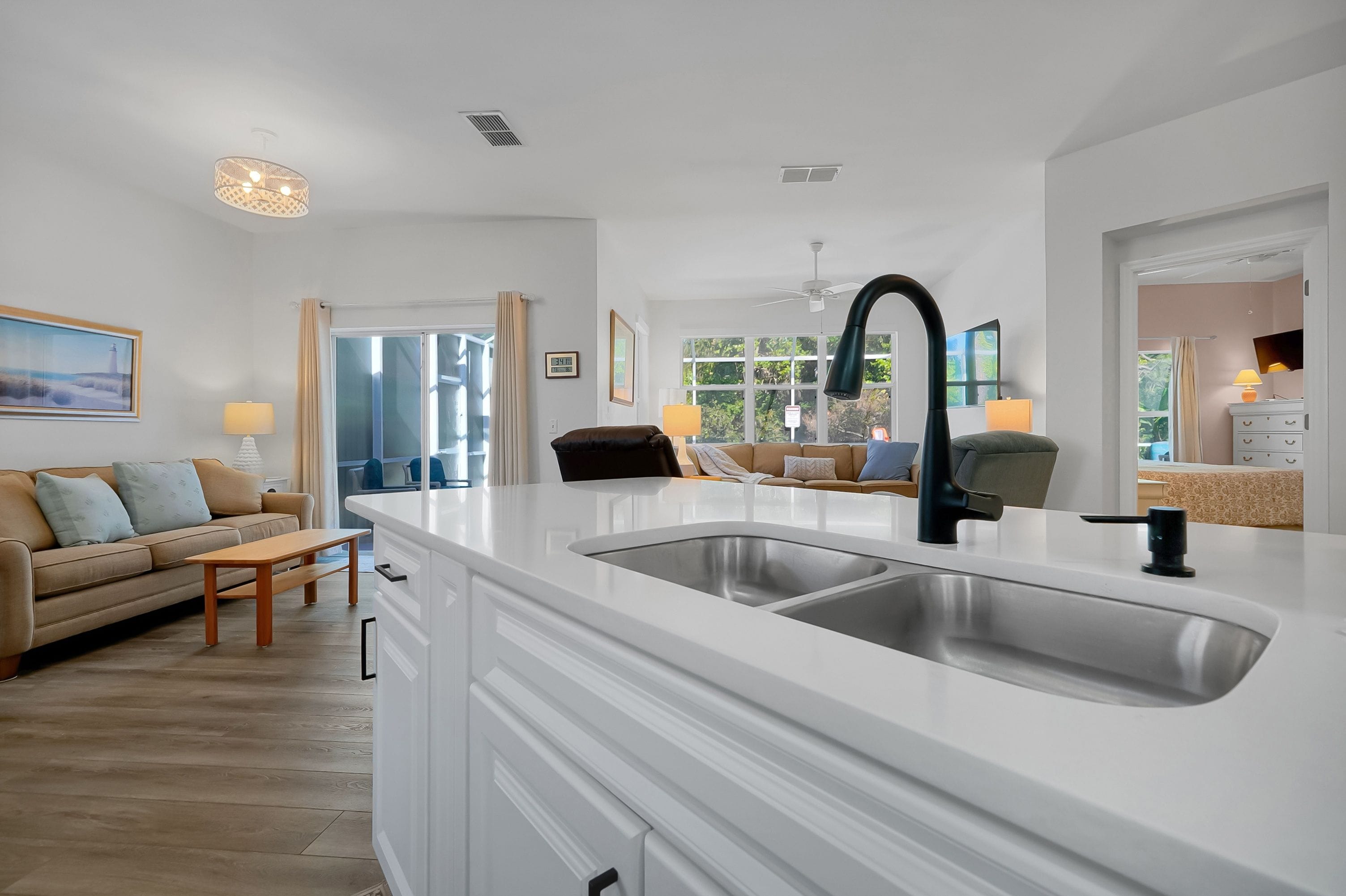 A modern kitchen with a white countertop, double sink, and a ceiling fan.