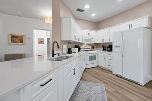 A modern kitchen with white cabinetry, a built-in oven, a microwave, and a refrigerator. - Updated 3br Disney-area Pool Home Private Screened Pool Peaceful Davenport 3 Bedroom Home (Davenport)