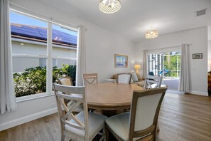 Une salle à manger avec une table ronde, des chaises et une vue sur l’extérieur.