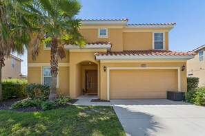 A two-story residential building with a garage, a palm tree, and a well-maintained lawn. - 8br Disney-area Resort Home, Private Pool, Game Room Sleeps 17,lazy River-7054 8 Bedroom Home (Davenport)