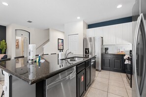 A modern kitchen with stainless steel appliances, a granite countertop, and a black backsplash. - 8br Disney-area Resort Home, Private Pool, Game Room Sleeps 17,lazy River-7054 8 Bedroom Home (Davenport)