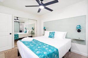 A hotel room with a bed, a ceiling fan, a mirror, and a nightstand. - Big Island Kahaluu Surf Boutique #2 2 Bedroom Apts (Kailua-Kona)