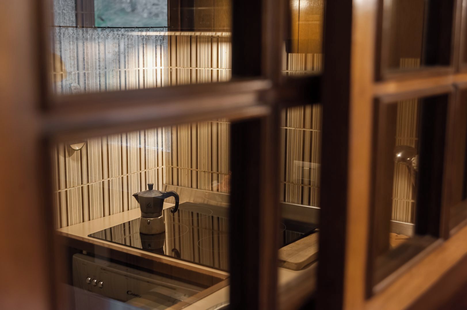 A room with a wooden cabinet, a metal pot, and a window with vertical blinds.