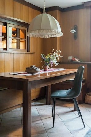 A wooden dining table with a vase of flowers, a chair, and a hanging light fixture. - Three-room apartment in Giomein, private garage, right on the slopes (Breuil-Cervinia)