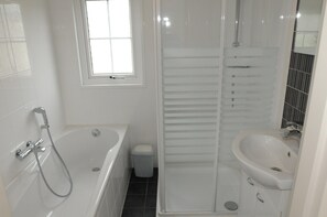Un bany amb banyera, plat de dutxa i un lavabo.