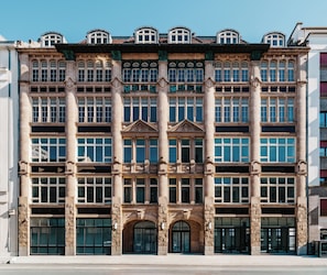Un edificio de varios pisos con estilo arquitectónico clásico, que presenta amplias ventanas y columnas decorativas.