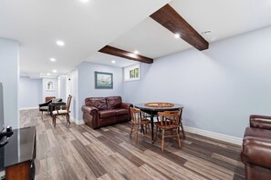 A spacious living area with a leather sofa, wooden dining table, and chairs. - Room for ten in the heart of Bayfield village (Bayfield)