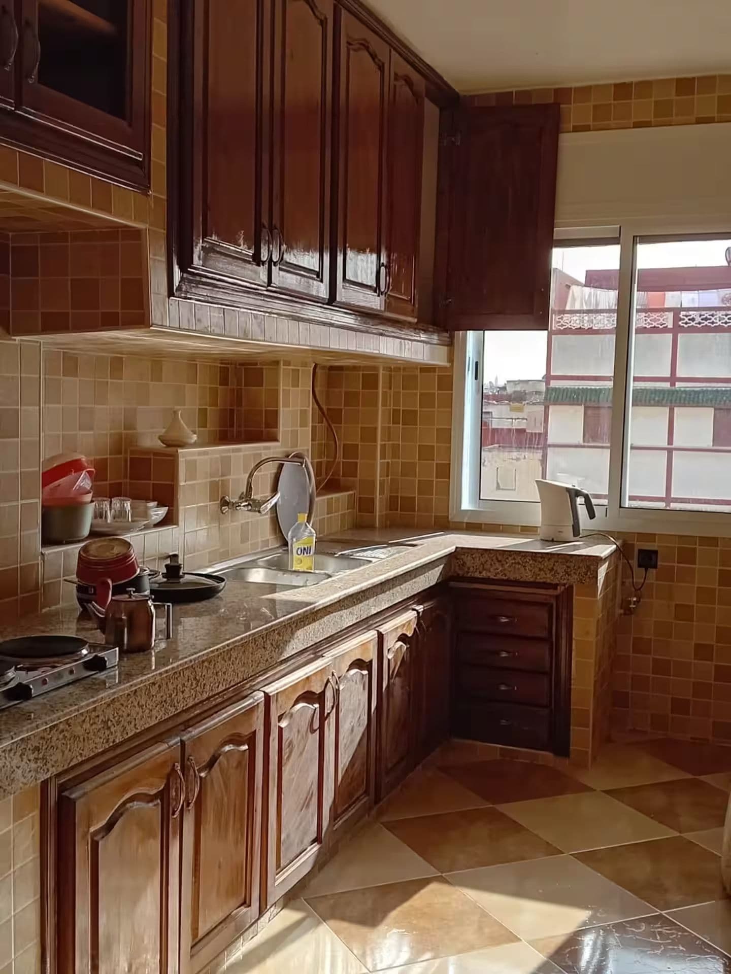 Eine Küche mit Holzausstattung, Arbeitsplatte, Spüle und Fenster.