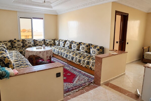 A living room with a sofa set, a round table, and a patterned rug.