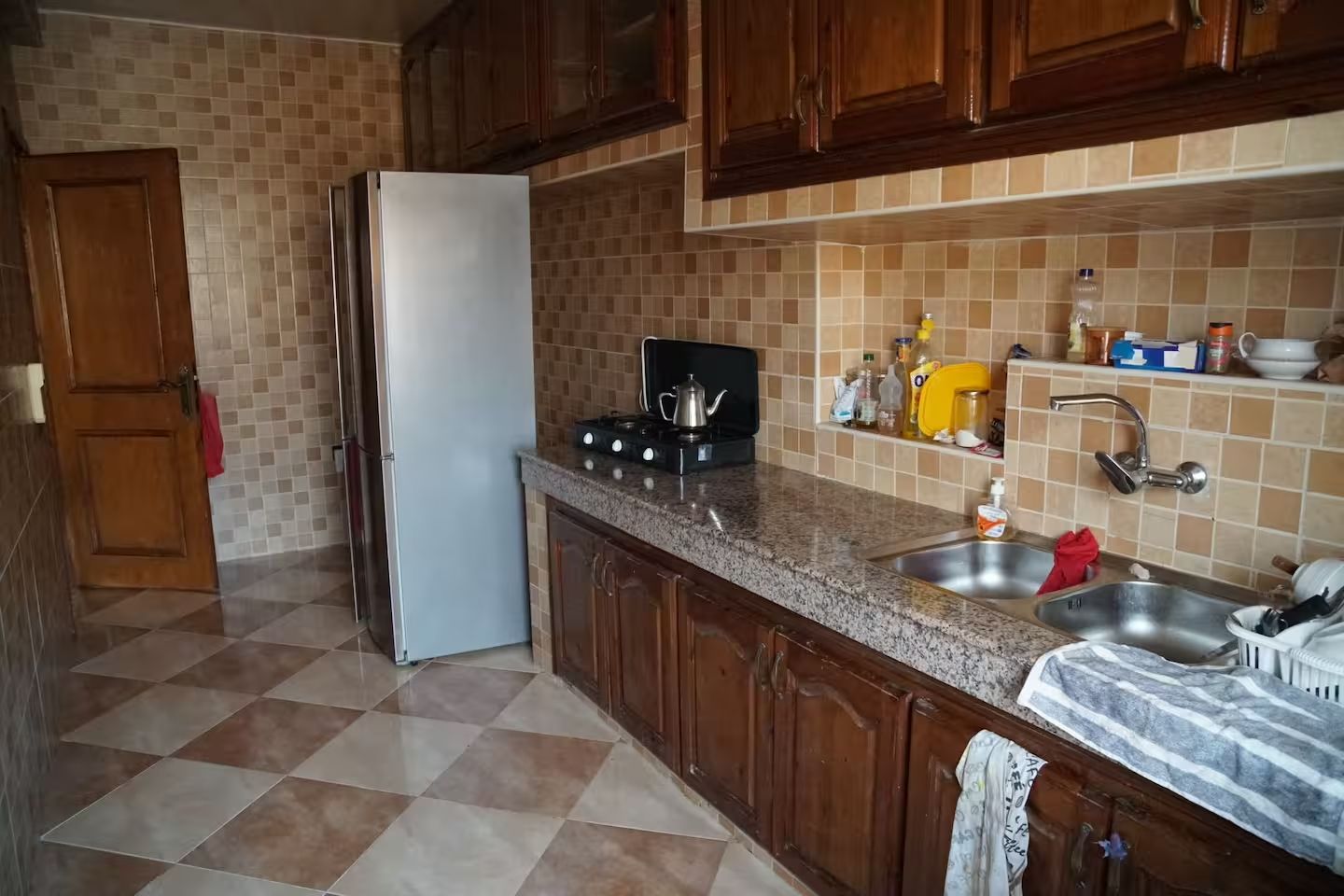 Eine Küche mit Kühlschrank, Herd, Spüle und einer gefliesten Spritzschutzwand.